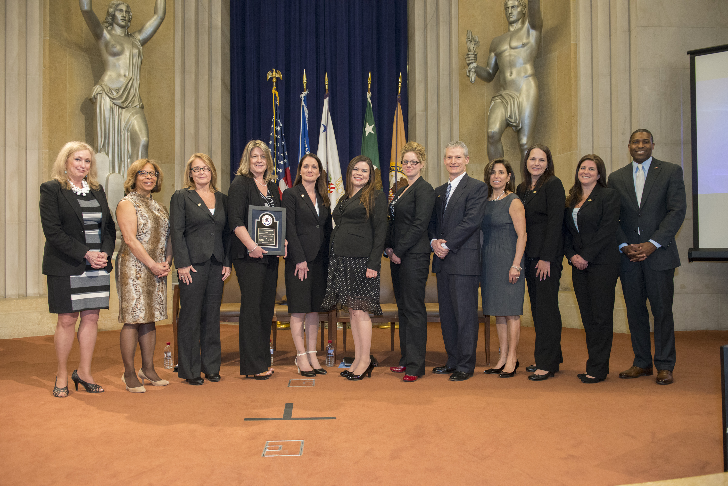 Staff from Christiana Care Health System's Forensic Nurse Examiner Team accept the 2014 Allied Professional Award. On stage with Joye E. Frost, Director, Office for Victims of Crime; Karol V. Mason, Assistant Attorney General, Office of Justice Programs; and Associate Attorney General Tony West are Anita Symonds, Christi Mench, Amy Stier, Christine Parks, Jennifer Oldham, Dr. Gordon Reed, Donna Lougheed, Erin Vaughn, and Jennifer Henry.