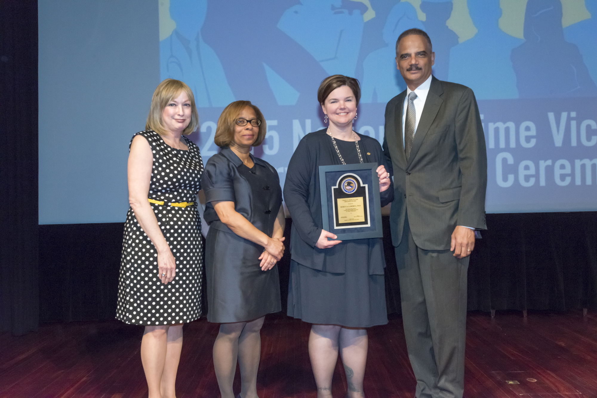Rebecca Campbell, Ph.D. receives the 2015 Vision 21 Crime Victim Research Award with (from left) Joye E. Frost, Director, Office for Victims of Crime; Karol V. Mason, Assistant Attorney General, and Attorney General Eric H. Holder, Jr.
