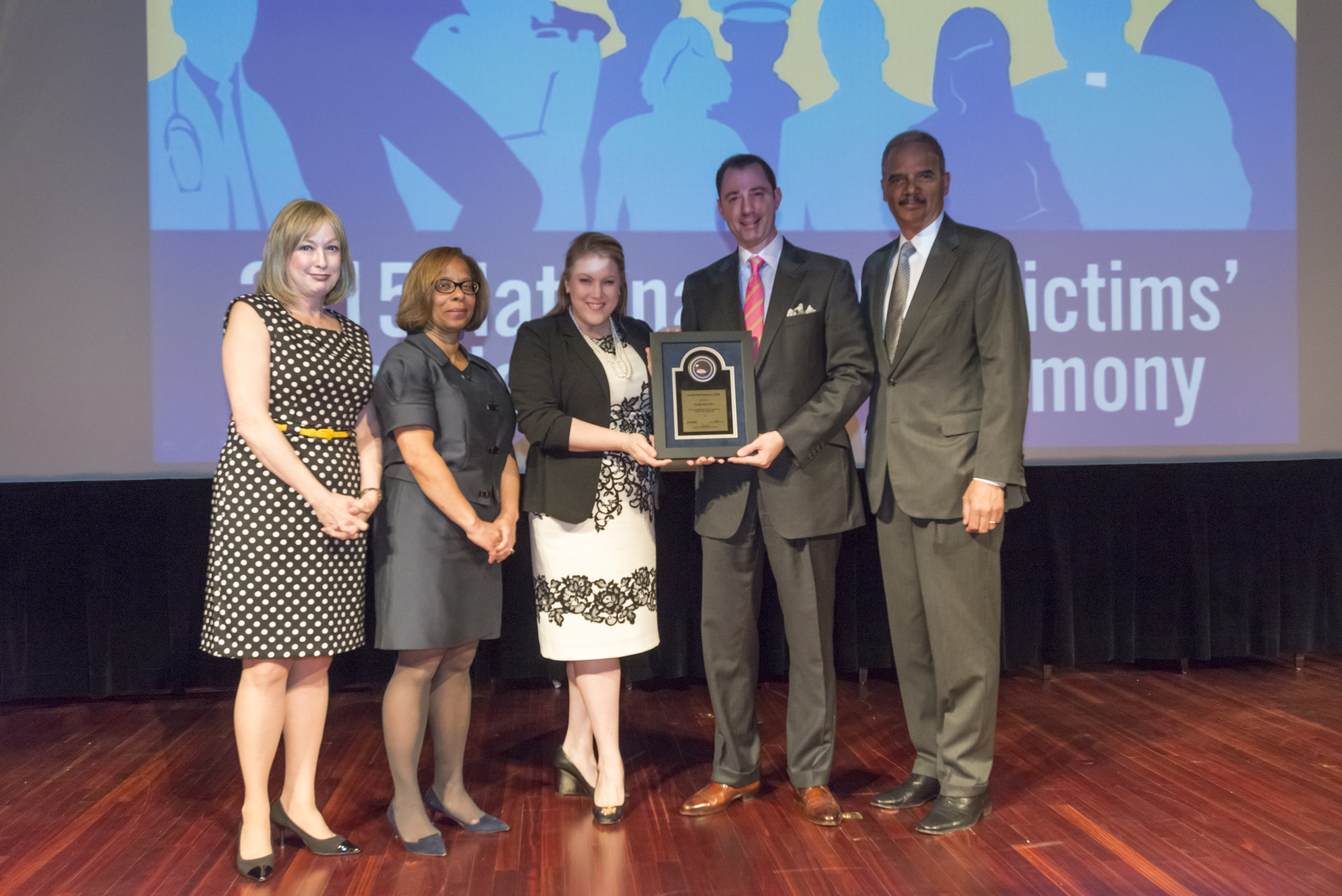 On behalf of Mary Kay Inc., Kirsten Gappelberg and Crayton Wendel Webb accept the 2015 Allied Professional Award with (from left) Joye E. Frost, Director, Office for Victims of Crime; Karol V. Mason, Assistant Attorney General, and Attorney General Eric H. Holder, Jr.