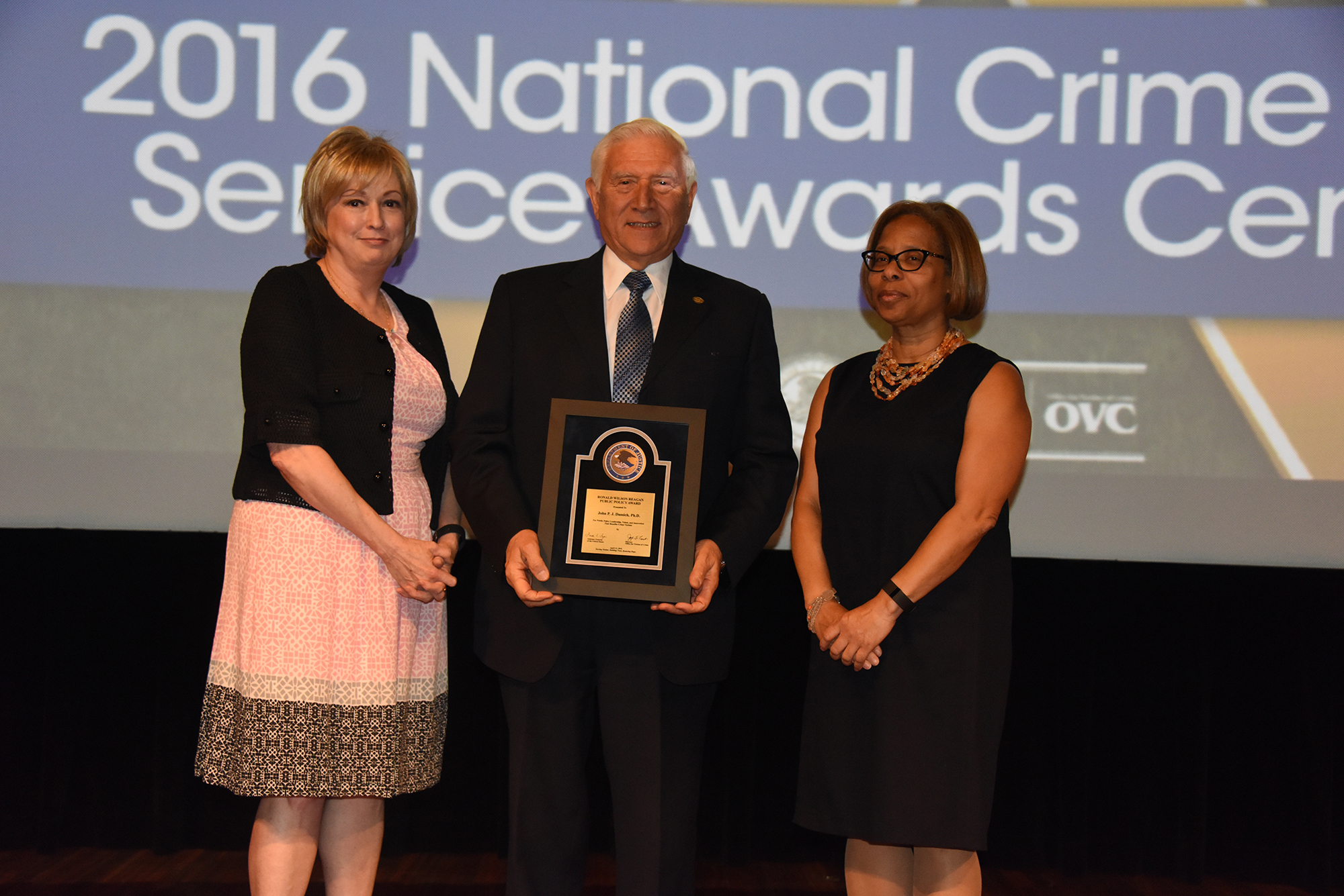 2016 Ronald Wilson Reagan Public Policy Award recipient Dr. John P.J. Dussich accepts the award with (from left) Joye E. Frost, Director, Office for Victims of Crime and Karol V. Mason, Assistant Attorney General.