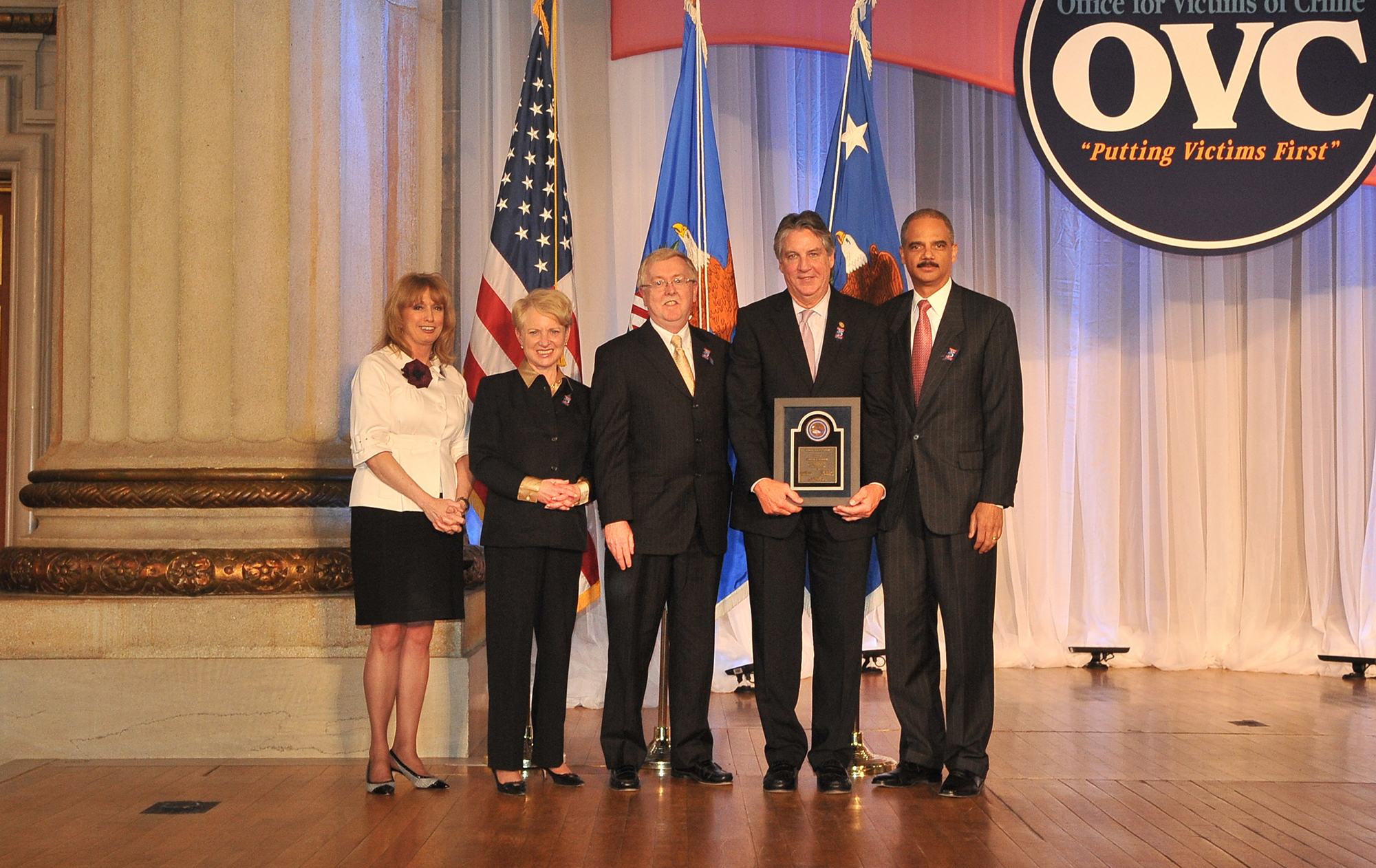 Award recipient Frank Marion displays his award with (from left) Joye E. Frost, Acting Director, Office for Victims of Crime; Laurie O. Robinson, Acting Assistant Attorney General, Office of Justice Programs; William Gilligan, Chief, U.S. Postal Inspection Service; and U.S. Attorney General Eric H. Holder, Jr.