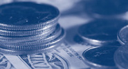 Photo of coins stacked on a dollar bill.