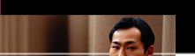 Photo of an Asian man sitting on a couch, resting his chin on his hand.