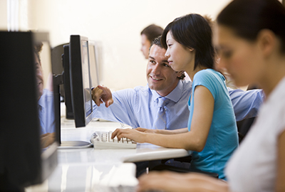 young woman sitting at computer terminal with instructor