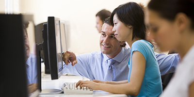 young woman sitting at computer terminal with instructor