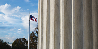 Pillars of justice in foreground, with flag pole and American flag in background