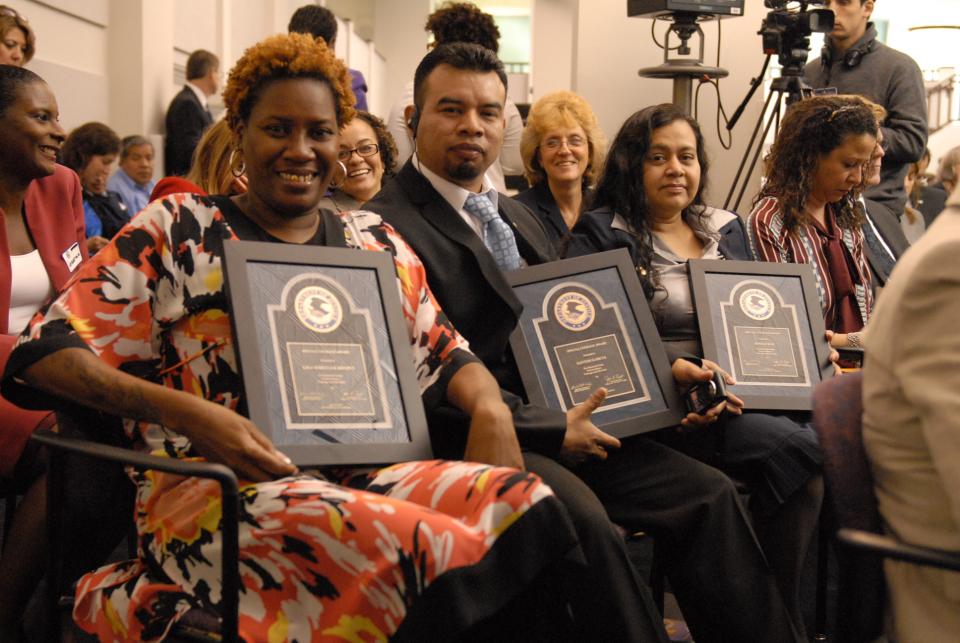 2013 award recipient Lisa Wheeler Brown (left), seated with award recipients Santos Garcia and Sonia Cruz holding plaques.