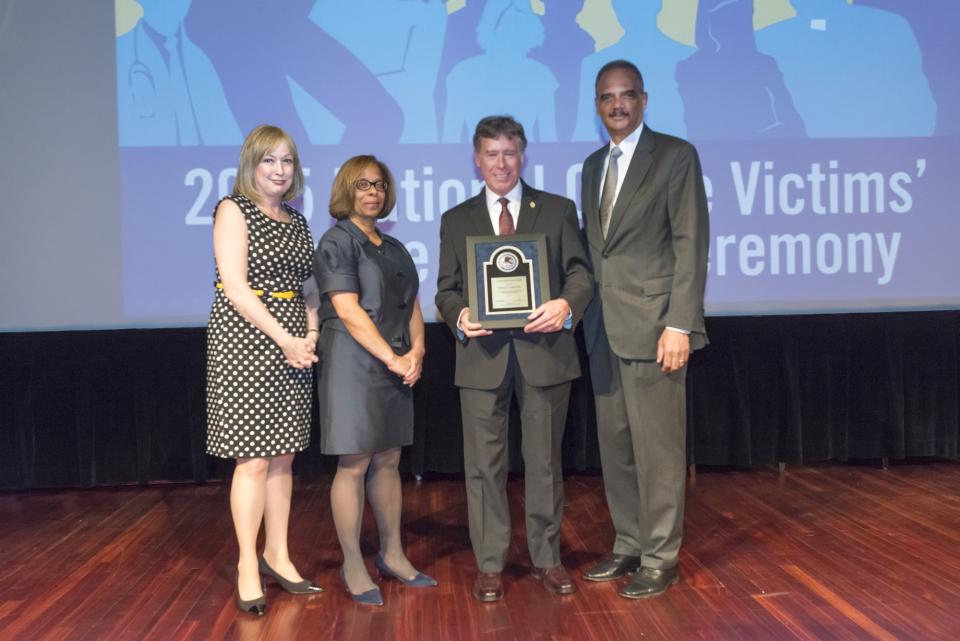 2015 National Crime Victim Service Award recipient Norman A. Gahn with (from left) Joye E. Frost, Director, Office for Victims of Crime; Karol V. Mason, Assistant Attorney General, and Attorney General Eric H. Holder, Jr.