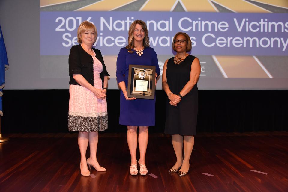 2016 Special Courage Award recipient Kim Case accepts the award with (from left) Joye E. Frost, Director, Office for Victims of Crime and Karol V. Mason, Assistant Attorney General.