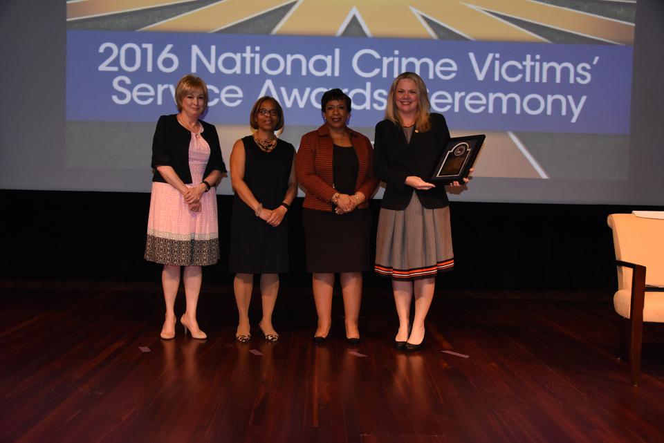 Staff from the National Domestic Violence Hotline accepts the 2016 Award for Professional Innovation in Victim Services. Katie Ray-Jones from the National Domestic Violence Hotline accepts the award with (from left) Joye E. Frost, Director, Office for Victims of Crime; Karol V. Mason, Assistant Attorney General, and Attorney General Loretta E. Lynch.