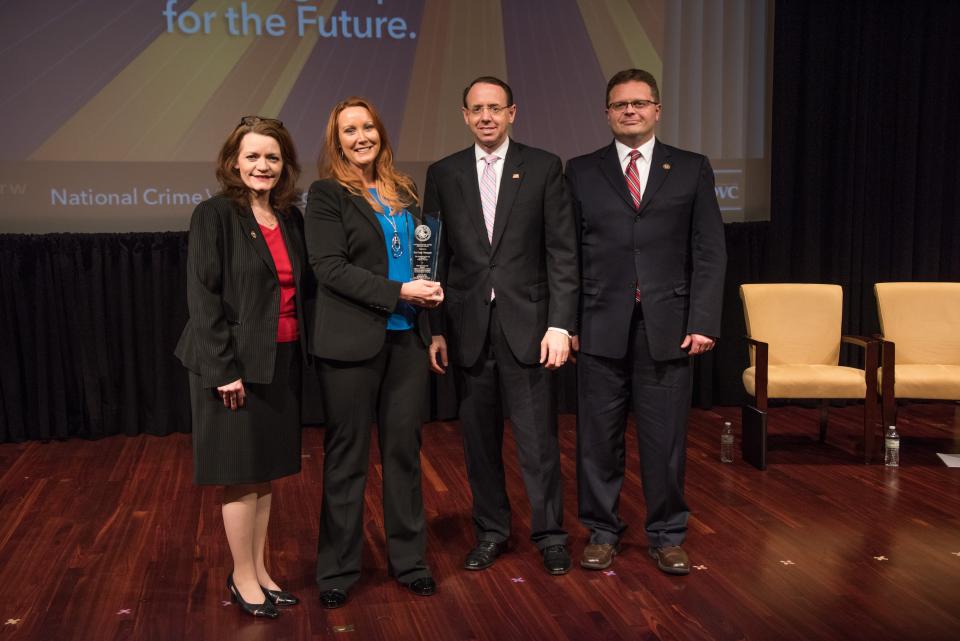 Eva Velasquez receives the 2019 National Crime Victim Service Award with (from left) OVC Director Darlene Hutchinson, Deputy Attorney General Rod J. Rosenstein, and Principal Deputy Assistant Attorney General for the Office of Justice Programs Matt M. Dummermuth.