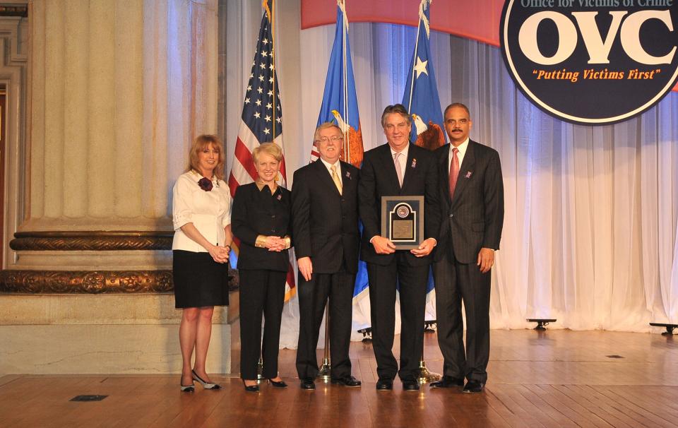 Award recipient Frank Marion displays his award with (from left) Joye E. Frost, Acting Director, Office for Victims of Crime; Laurie O. Robinson, Acting Assistant Attorney General, Office of Justice Programs; William Gilligan, Chief, U.S. Postal Inspection Service; and U.S. Attorney General Eric H. Holder, Jr.