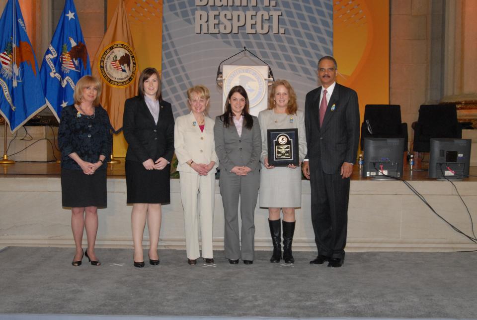 Accepting the 2010 National Crime Victim Service Award on behalf of the Americans Overseas Domestic Violence Crisis Center, Paula Lucas, Brooke Galloway, and Caitlin McGuan are pictured with (from left) Joye E. Frost, Acting Director, Office for Victims of Crime; Assistant Attorney General Laurie O. Robinson, Office of Justice Programs; and U.S. Attorney General Eric H. Holder, Jr.