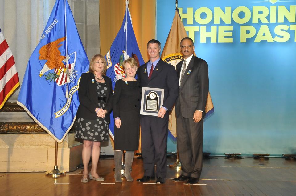Brooks Douglass receives the 2011 Ronald Wilson Reagan Public Policy Award, standing with (from left) Joye E. Frost, Acting Director, Office for Victims of Crime; Assistant Attorney General Laurie O. Robinson, Office of Justice Programs; and U.S. Attorney General Eric H. Holder, Jr.