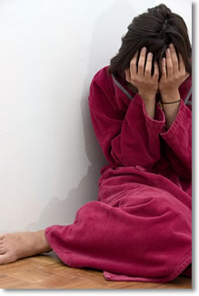 Photo of a woman sitting on the floor with her hands over her face