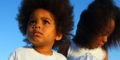 young boy and girl wearing white clothes and sitting in sand young boy and girl wearing white clothes and sitting in sand