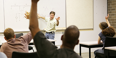adult students with raised hands face instructor at white board adult students with raised hands face instructor at white board