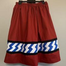 Deep red skirt with blue and white ribbons stitched along the bottom. 